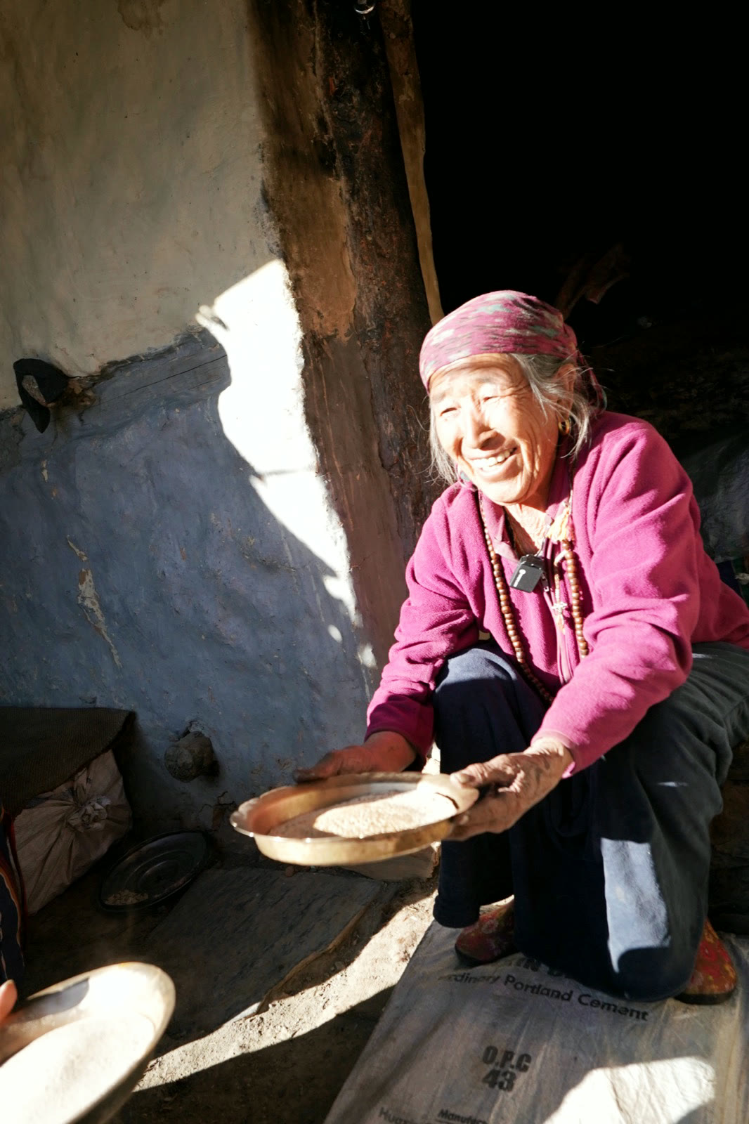 一位村中婦人在屋內篩穀,光從高處落下